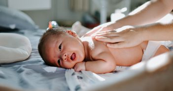Pourquoi bébé pleure après chaque repas ? Maman qui masse le dos de son bébé