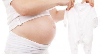 Les indispensables du trousseau de bébé Femme enceinte qui choisit un pyjama pour le trousseau de naissance de son bébé