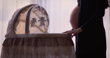 Préparer l’arrivée de bébé sans se ruiner Femme enceinte qui prépare le berceau pour l'arrivée de son bébé