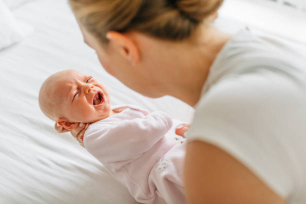 Bébé qui pleure dans les bras de sa maman