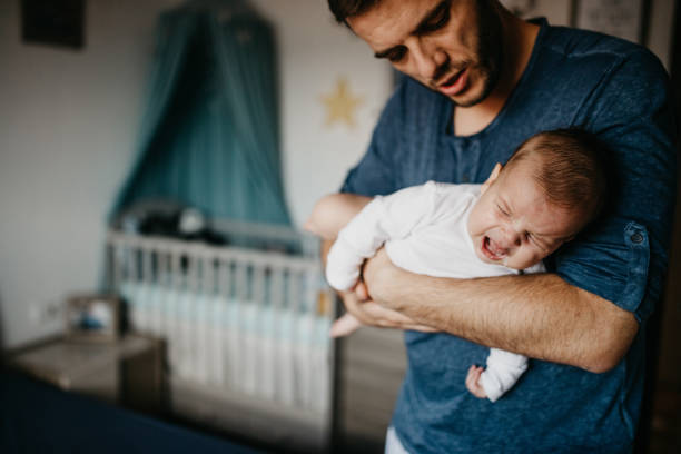 Bébé qui souffre de coliques dans les bras de son papa